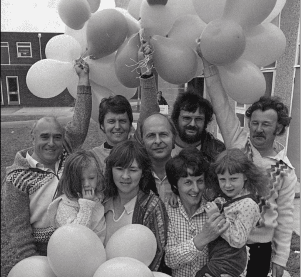 A group of people stood outside, holding balloons