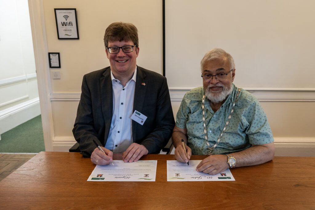 Image 1: Björn Gryschka, Mayor of Bad Salzdetfurth (left), and Councillor Aziz Chowdhry, Mayor and Chair of Yate Town Council (right) signing 40th anniversary certificate